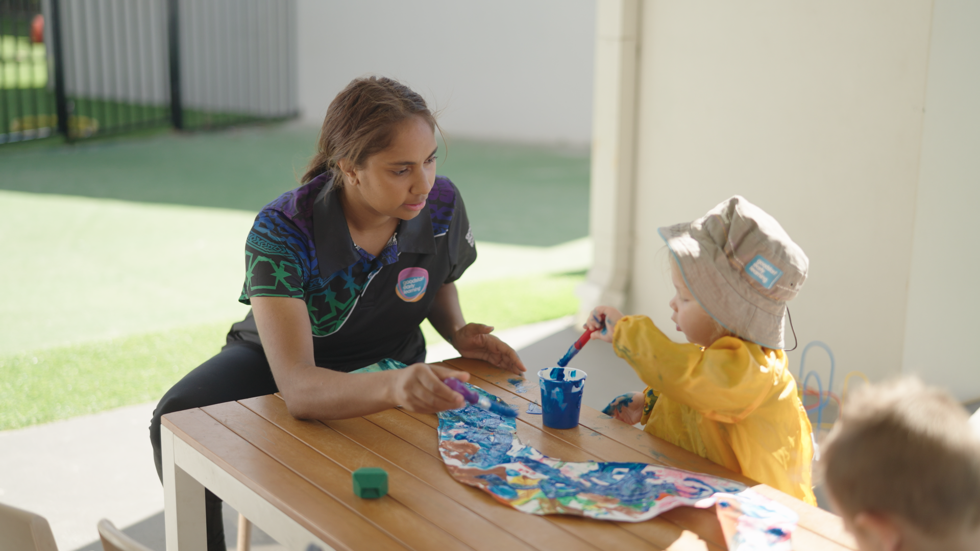 Djilawaa, trainee educator at Goodstart Stratton, working on some art with a child at the centre
